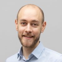 Fabian Streicher - Senior Consultant System Integration: Smiling man with beard and green-grey eyes